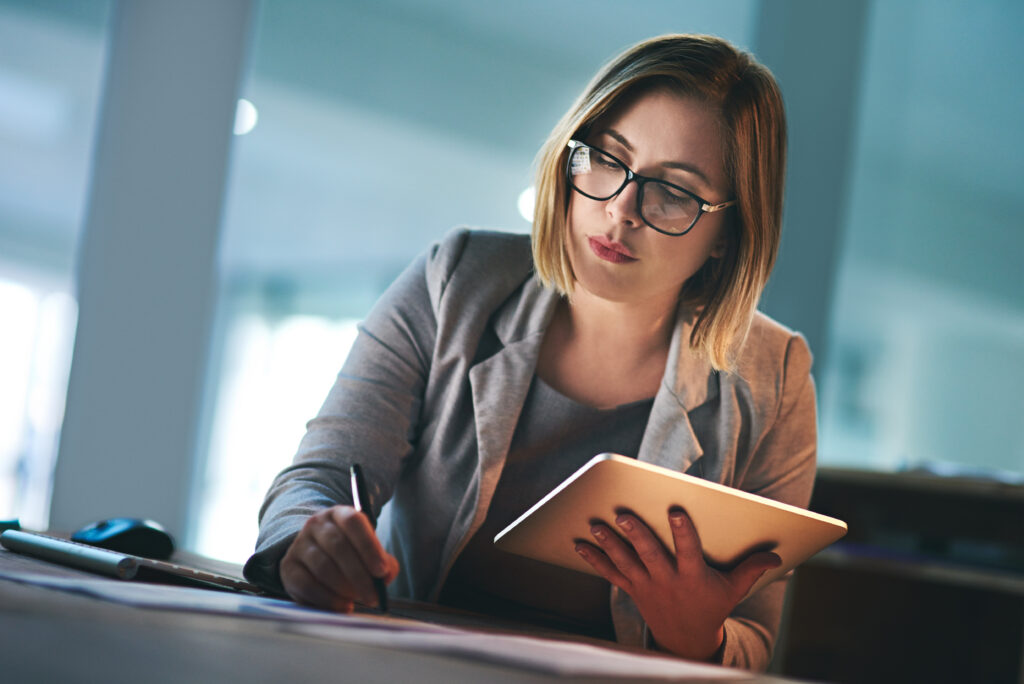 shot of a young businesswoman working late on a digital tablet in an office.